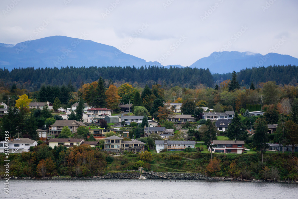 Campbell River, Vancouver Island, British Columbia, Canada. Beautiful view of residential homes on the ocean shore during a cloudy evening.