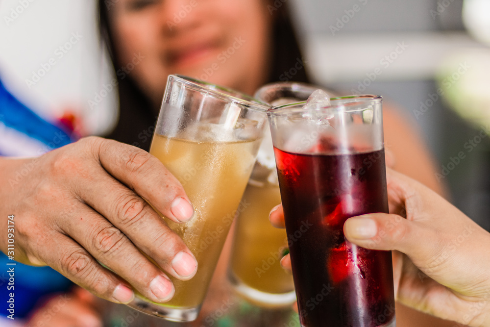 three persons are  toasting with glasses of fresh fruit water 