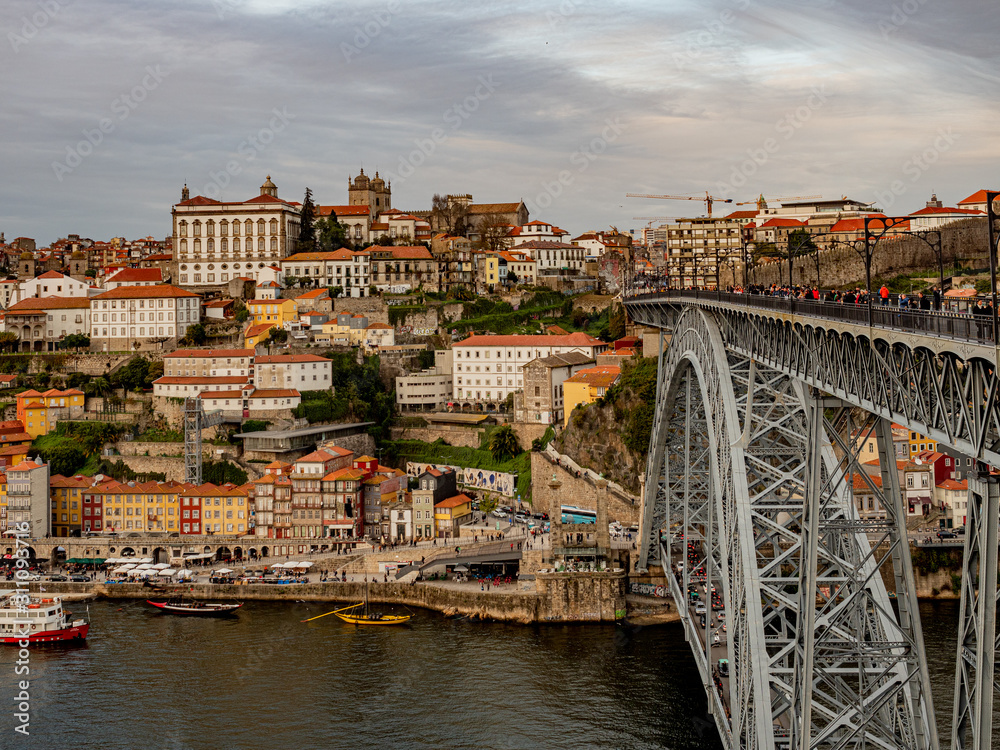 Obraz premium Porto, Portugal. 16 November 2019. Colorful skyline of the old town at sunset seen from other side of river Douro with Ponte Luis I in the foreground.