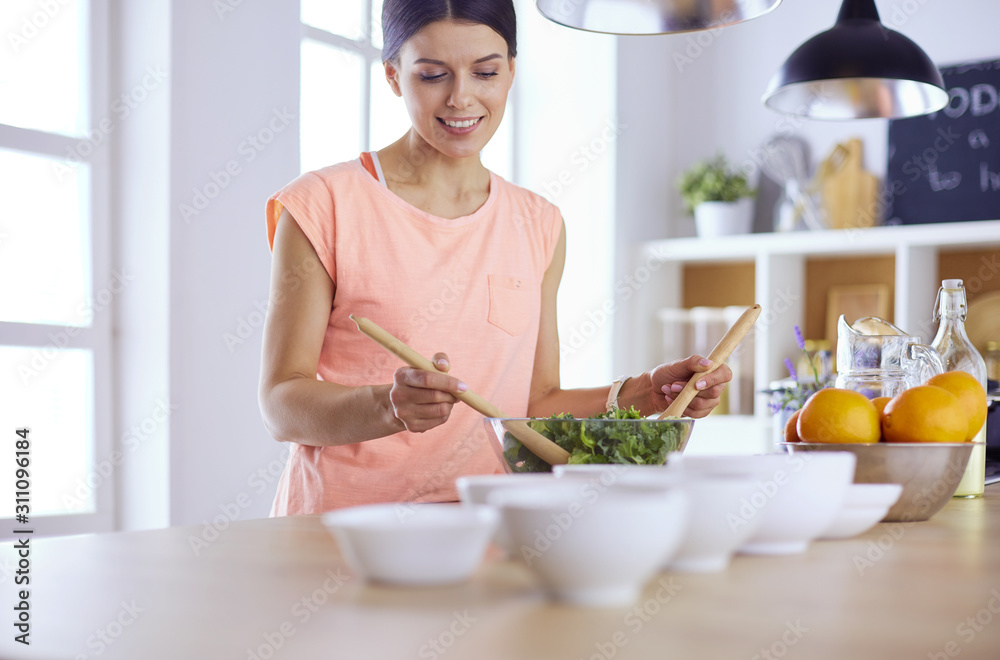 Smiling young woman mixing fresh salad in the kitchen. Smiling young woman mixing fresh salad in the kitchen.