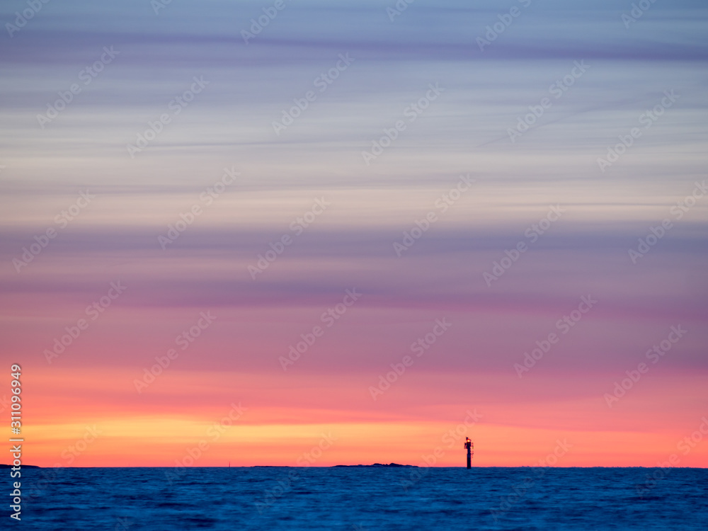 A very colorful sunset over a small lonely lighthouse on an island A very colorful sunset over a small lonely lighthouse on an island