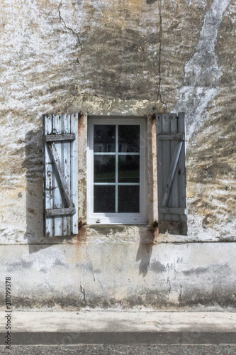 Stone wall. Preservation of the facade of a historic building. Empty window opening. Medieval Europe. Ruined house. Iron door. The wall of an ancient fortress. Stone castle.