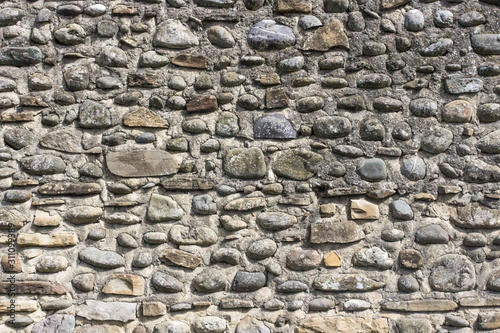 Stone wall. Masonry stones. Building construction. Medieval construction technology. The exterior of the building. The texture of the stones. An element of architecture. Brick background.