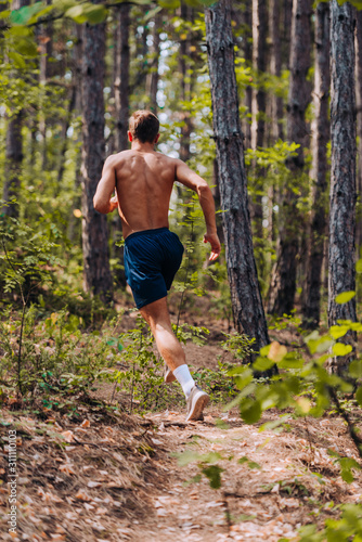 Shirtless male athlete fitness runner sprinting fast outside.Trail running concept