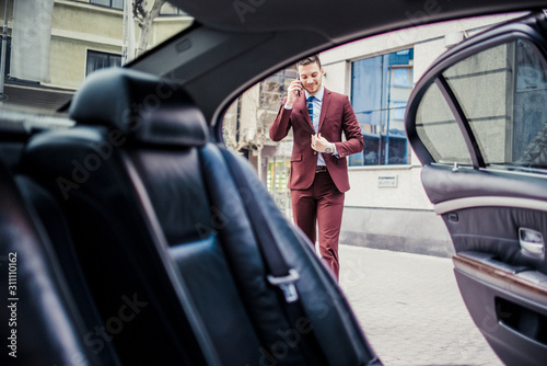 Fotografiet Businessman talking on mobile near the limo