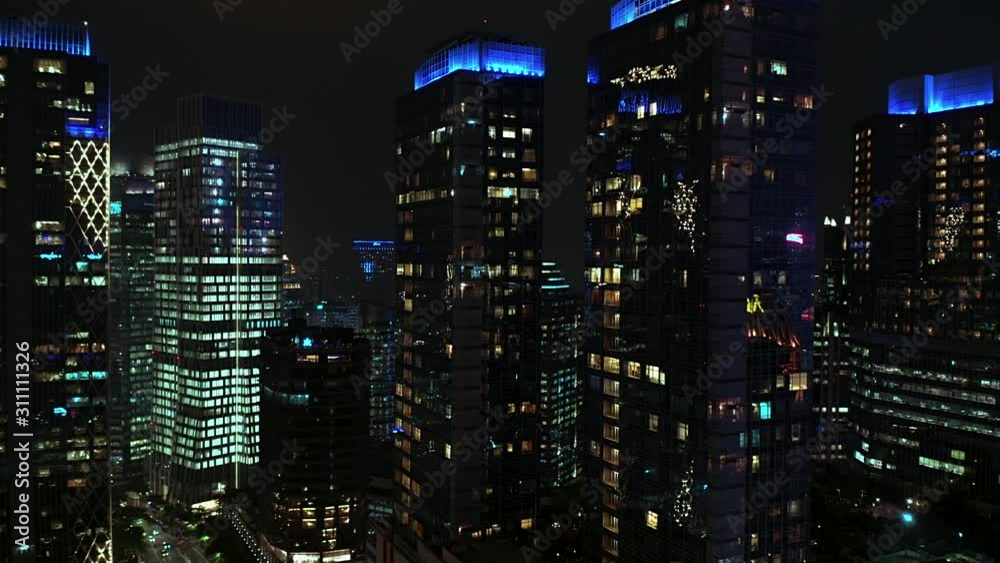 JAKARTA, Indonesia - December 18, 2019: Exotic aerial modern skyscrapers exterior at night with glass windows and night lights. Shot in 4k resolution from a drone flying forwards JAKARTA, Indonesia - December 18, 2019: Exotic aerial modern skyscrapers exterior at night with glass windows and night lights. Shot in 4k resolution from a drone flying forwards