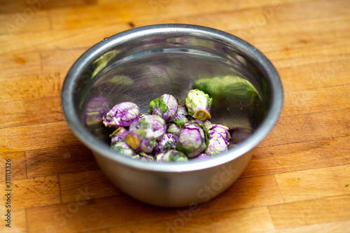 Purple brussels sprouts in stainless steel mixing bowl