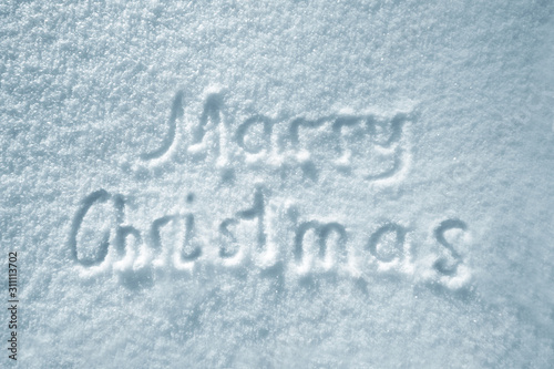 Text Marry Christmas on snow. Winter background, inscription Marry Christmas on snowy surface, natural  texture, hand lettering, top view