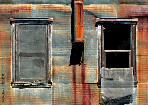 Old rusted corrugated metal walls for fire protection, windows and heater vent on building in Old Isleton, California  photo