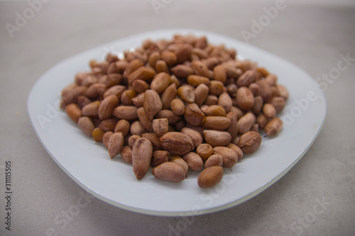 Peanuts on a white plate on a gray kitchen table closeup