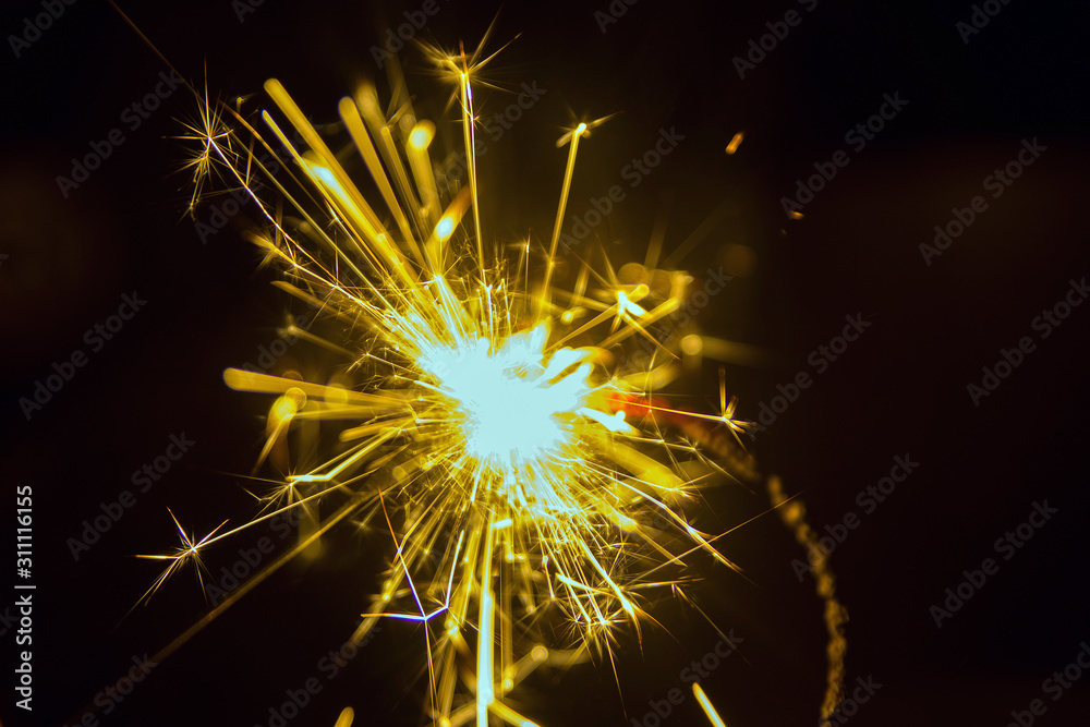 Sparks of a burning sparkler close-up on a black background macro bokeh