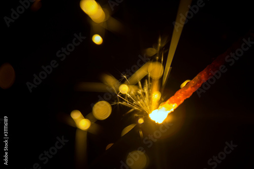Sparks of a burning sparkler close-up on a black background macro bokeh