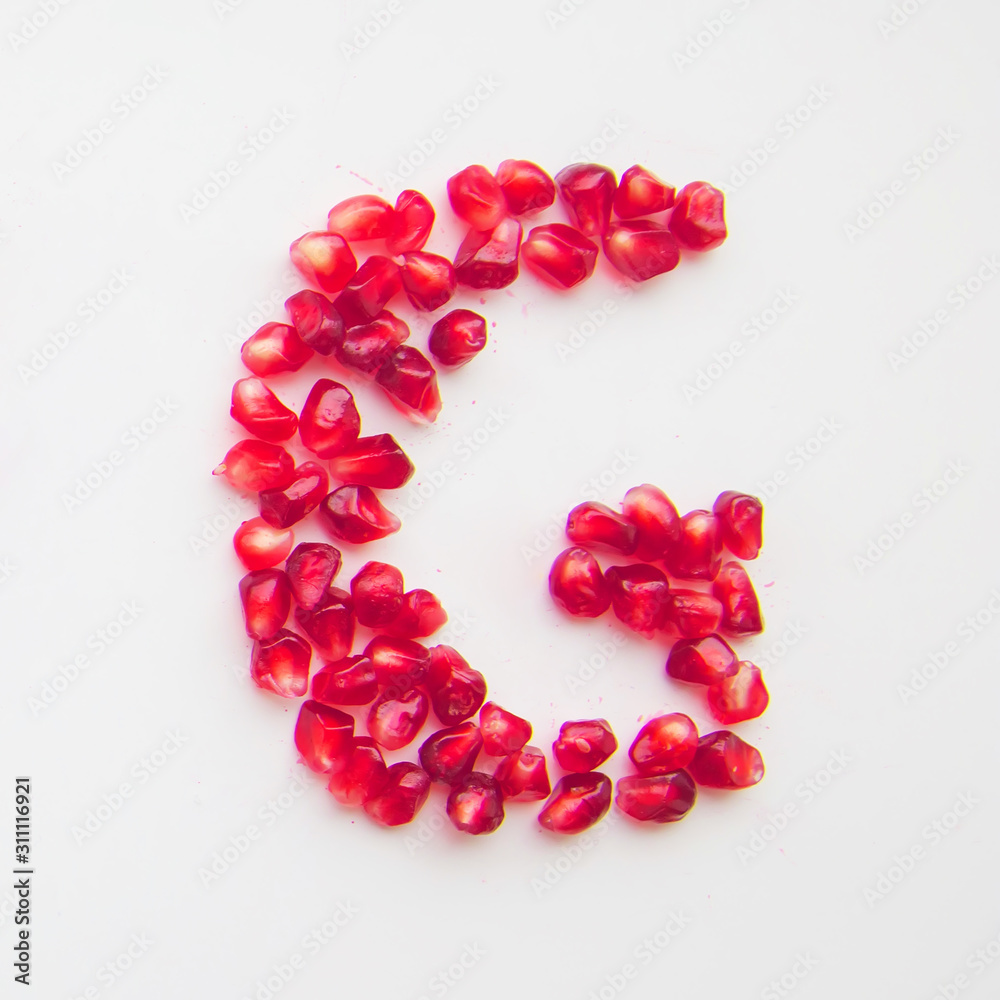letter G folded from pomegranate berries on a white background top view letter G folded from pomegranate berries on a white background top view
