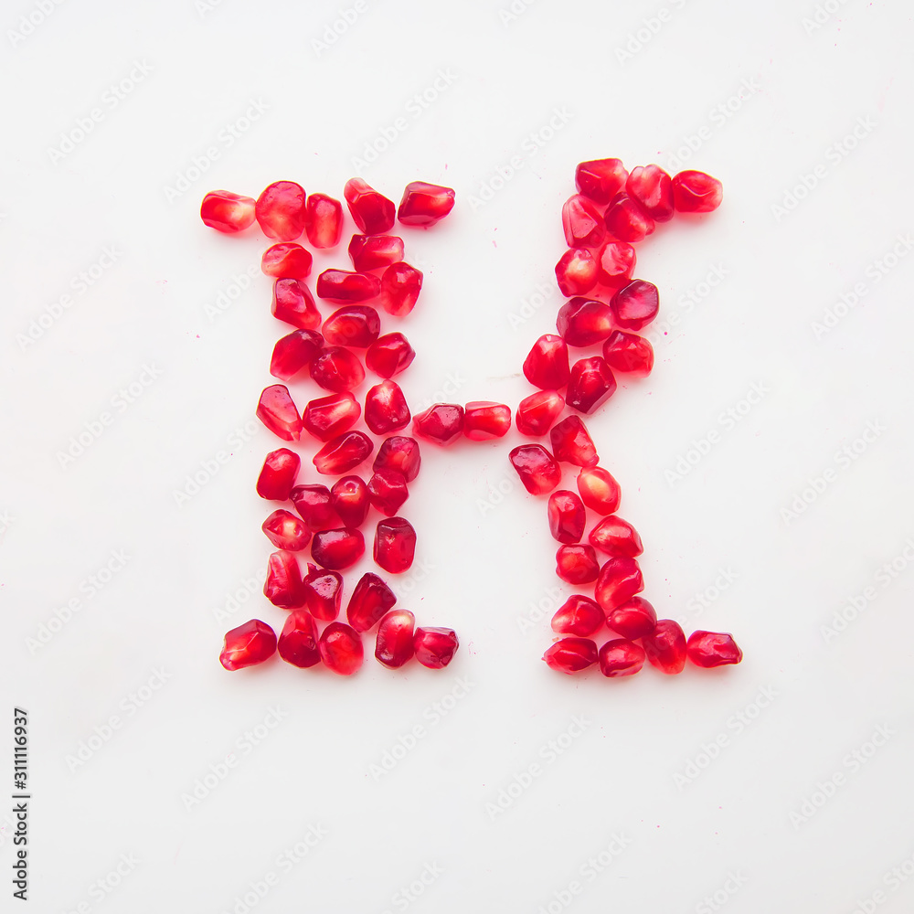 letter K folded from pomegranate berries on a white background top view letter K folded from pomegranate berries on a white background top view