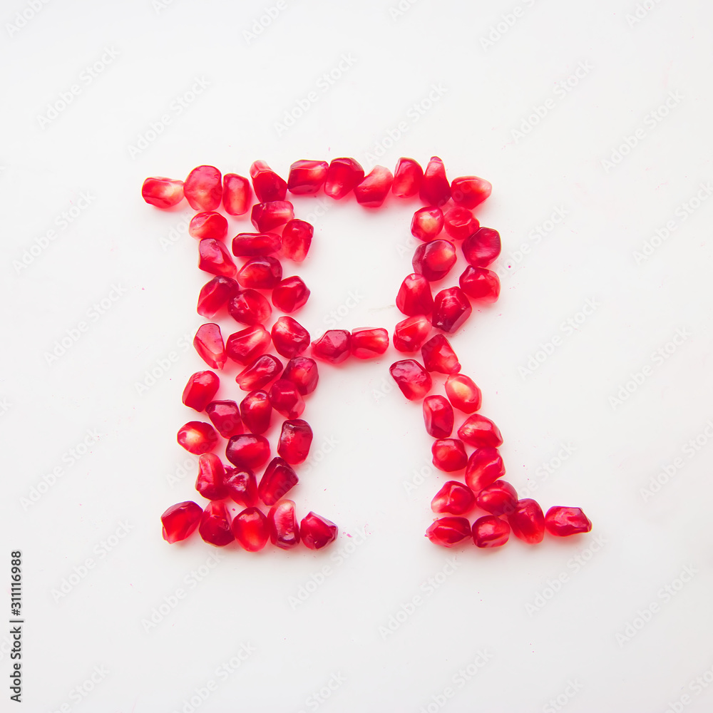 letter R folded from pomegranate berries on a white background top view letter R folded from pomegranate berries on a white background top view