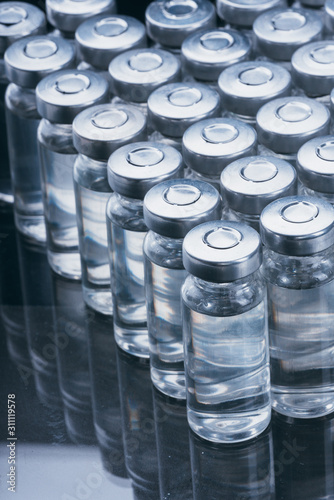 Glass medical ampoule vial for injection. Medicine is dry white drug penicillin powder or liquid with of aqueous solution in ampulla. Close up. Bottles ampule with aluminum cap on backgrounds gray.