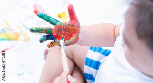 Happy asian baby child use paintbrush draw water color or fingerpaint on hand