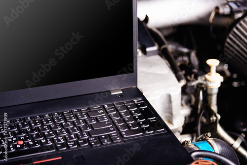 Laptop computer on car mechanic engine for service