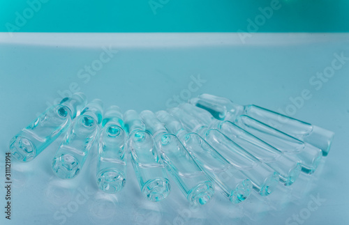Wallpaper Mural Glass medical ampoule vial for injection. Medicine is liquid sodium chloride with of aqueous solution in ampulla. Close up. Bottles ampule multicolor on background color and water. Human plasma. Torontodigital.ca