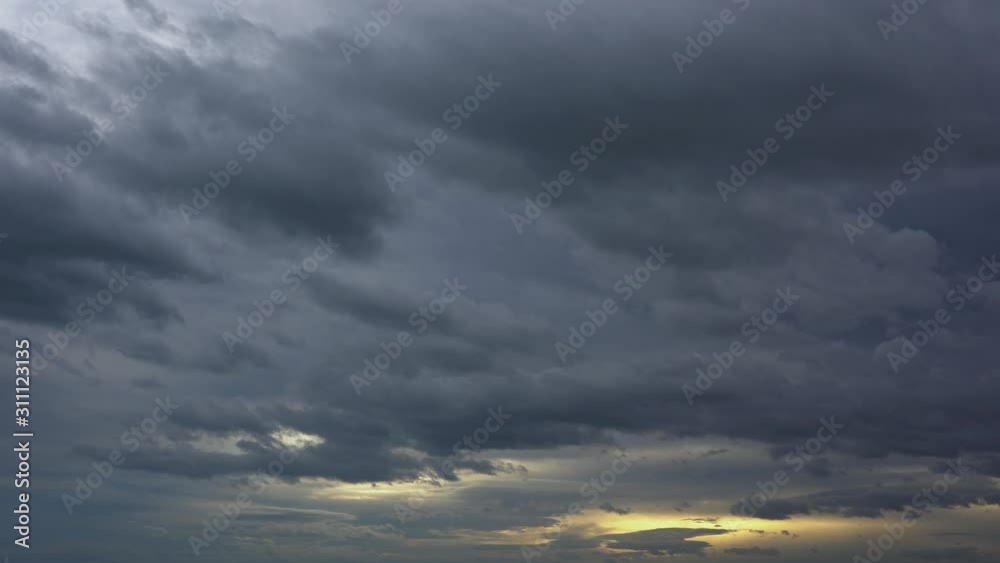 Time lapse, dark storm clouds passing through the sky with golden sunset reflections Time lapse, dark storm clouds passing through the sky with golden sunset reflections