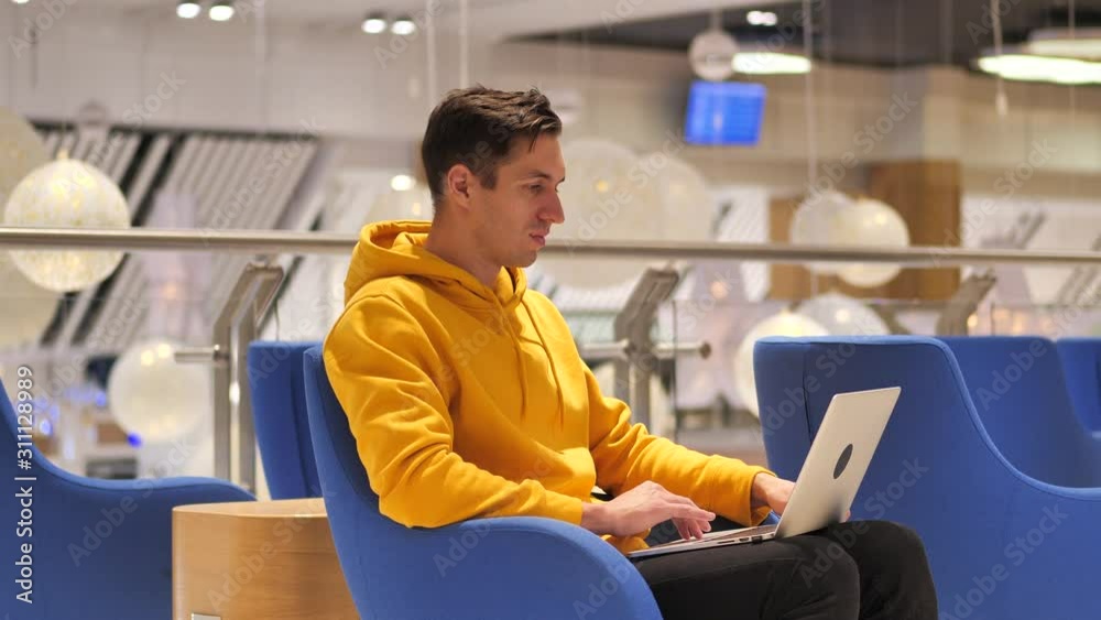 young man working at laptop in a large modern cafe young man working at laptop in a large modern cafe
