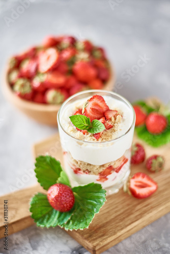 Strawberry granola or smoothie in a glass and fresh berries in wooden bowl, top view. Healthy breakfast