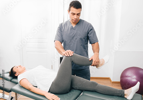 Woman treatment her joint with therapist. Physical therapist helping his patient doing exercise for treatment hip joint