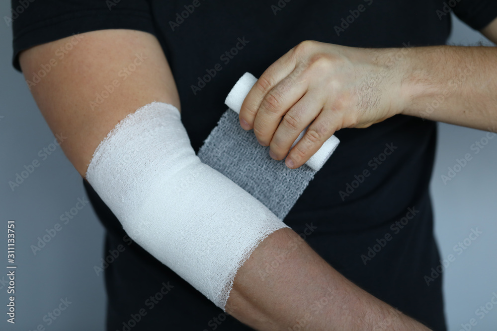 Male hand with tight elastic bandage on elbow closeup