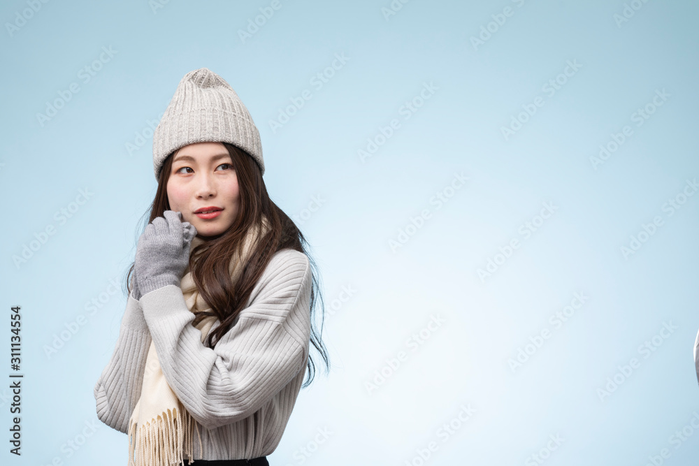 水色を背景にした冬服を着た若い女性のポートレート