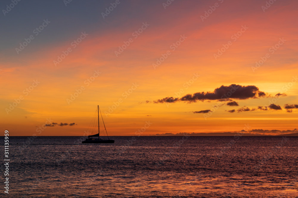 Sailboat anchored in a Maui channel during a beautiful Hawaiian sunset.