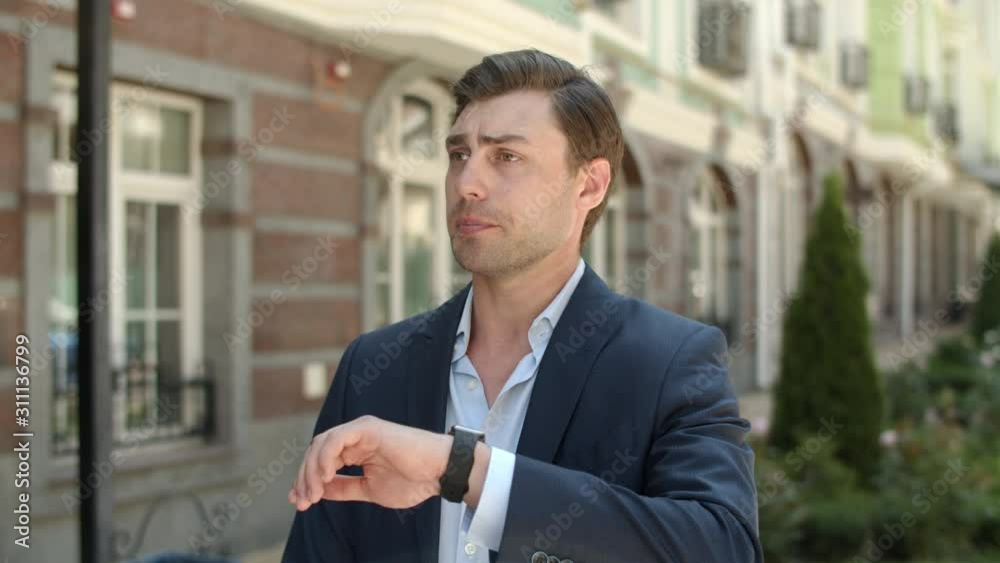 Closeup man waiting for partner at street. Man checking time on smart watch Closeup man waiting for partner at street. Man checking time on smart watch
