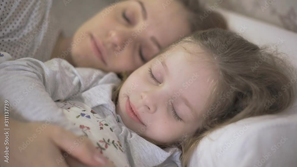 mother and young daughter sleeping in bed and hugging each other ,the relationship between parents and children mother and young daughter sleeping in bed and hugging each other ,the relationship between parents and children