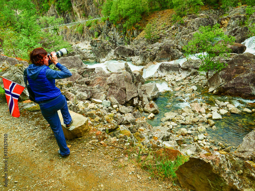 Tourist with norwegian flag on mountains path