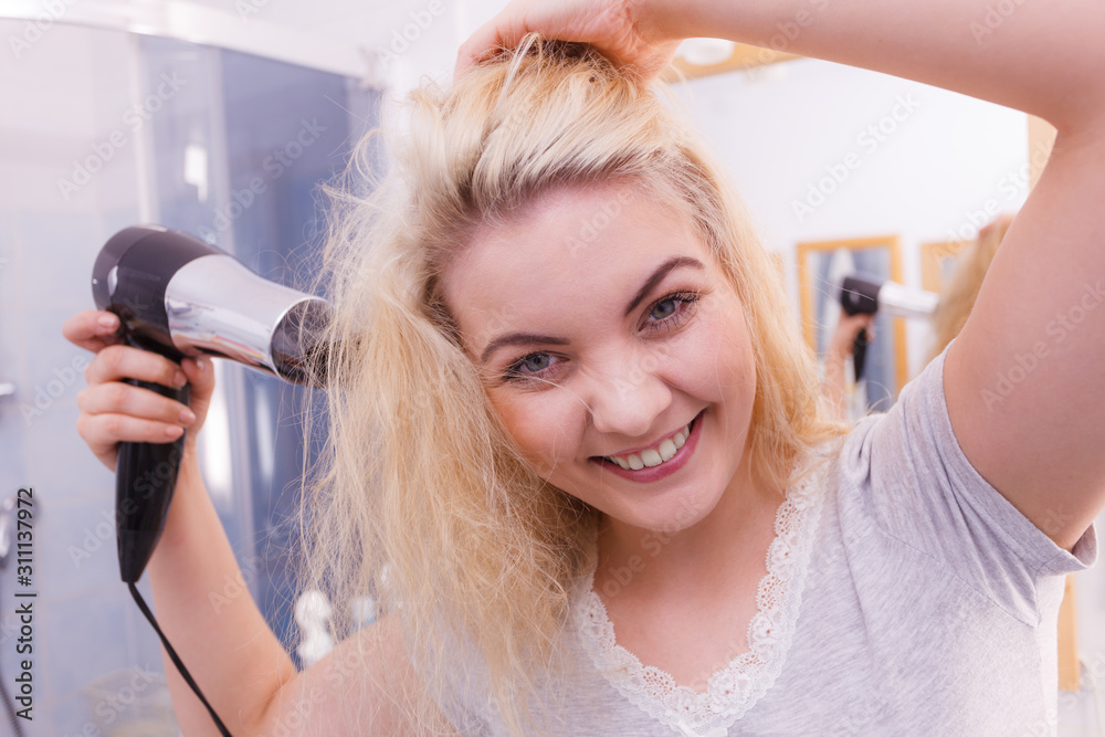 Woman drying hair in bathroom Woman drying hair in bathroom
