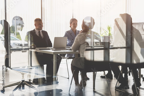 Silhouettes of people sitting at the table. A team of young businessmen working and communicating together in an office. Corporate businessteam and manager in a meeting