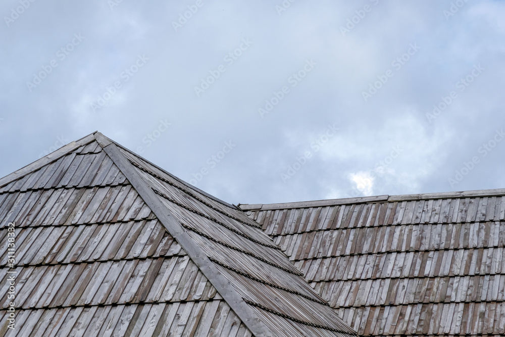 Wooden roof with cloudy sky in background.