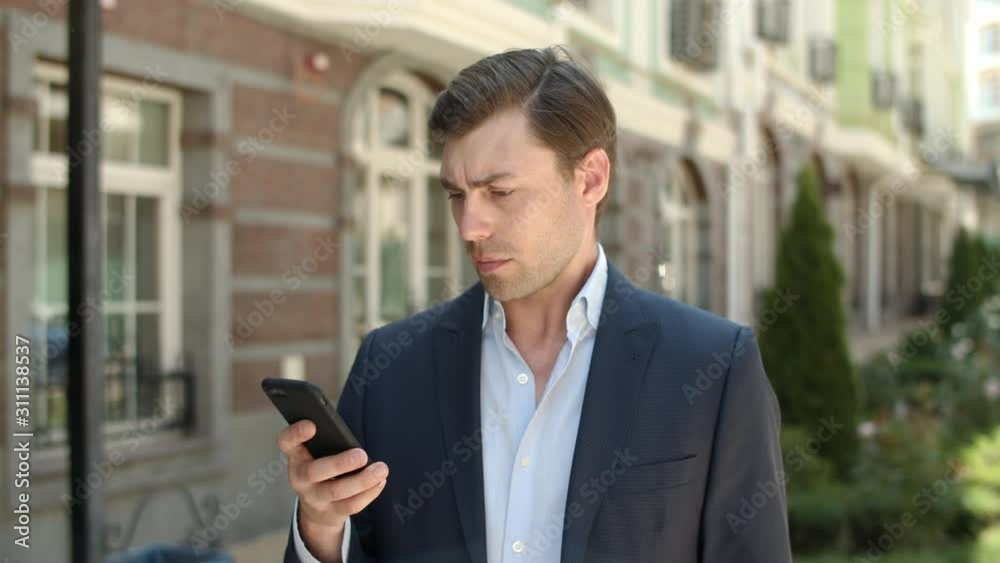 Closeup businessman typing messages at street. Man using smartphone at street Closeup businessman typing messages at street. Man using smartphone at street