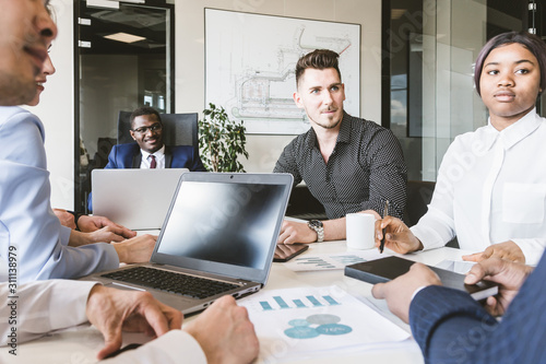 A team of young businessmen working and communicating together in an office. Corporate businessteam and manager in a meeting.