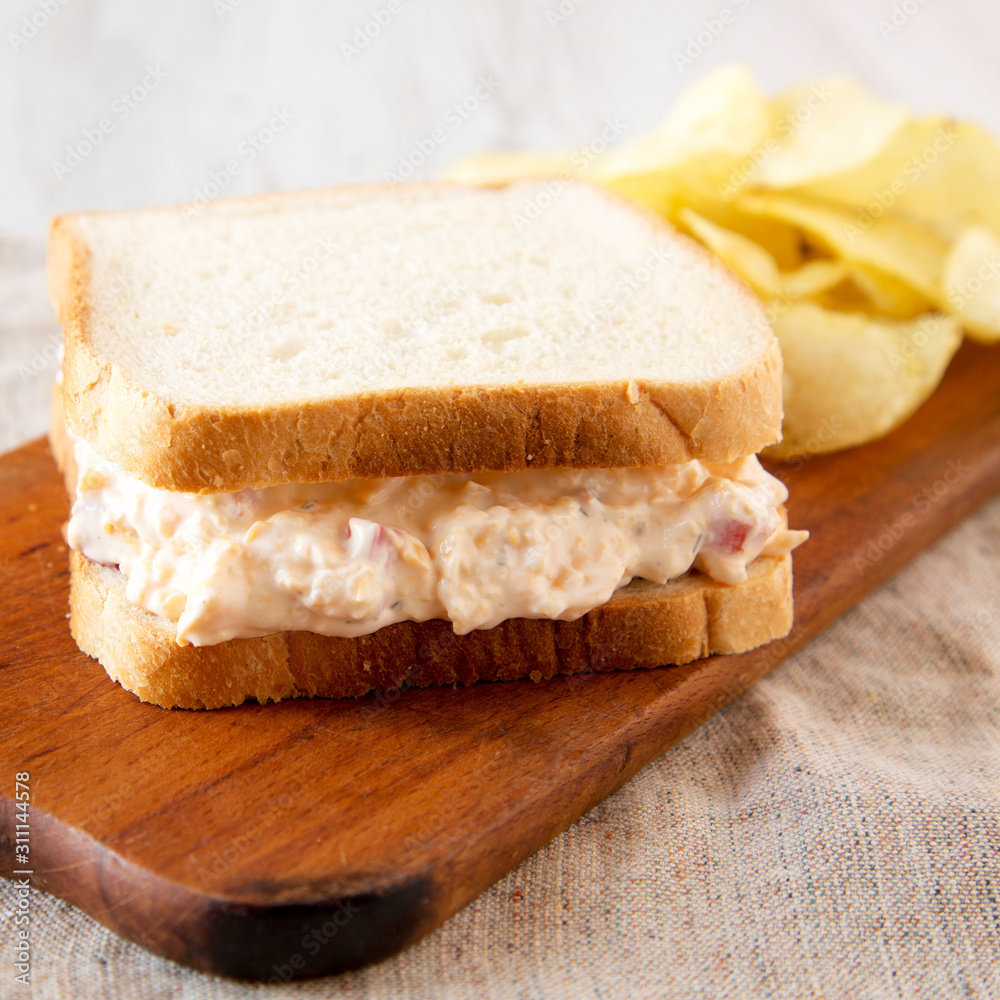 Tasty Homemade Pimento Cheese Sandwich with chips on a rustic wooden board, side view. Close-up.