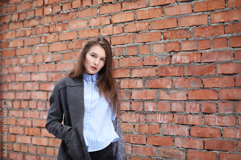 Young beautiful girl near red brick wall posing