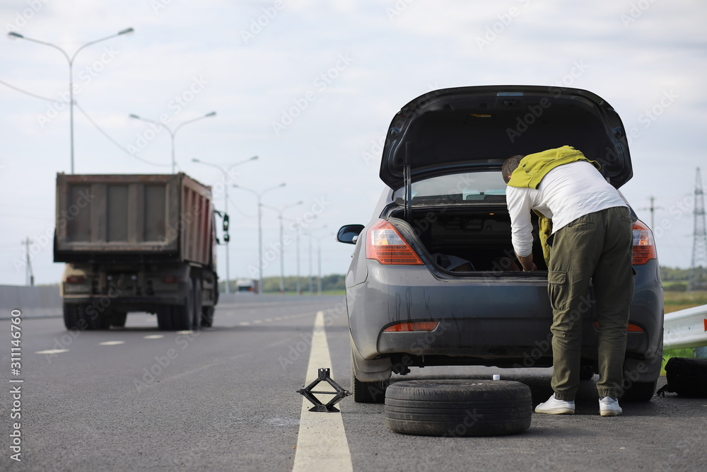 Replacing the wheel of a car on the road. A man doing tire work on the sidelines. Replacing the wheel of a car on the road. A man doing tire work on the sidelines.