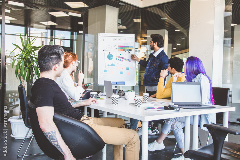 Group of multi ethnic executives discussing during a meeting. Business man and woman sitting around table at office and smiling. A team of young creative designers Group of multi ethnic executives discussing during a meeting. Business man and woman sitting around table at office and smiling. A team of young creative designers