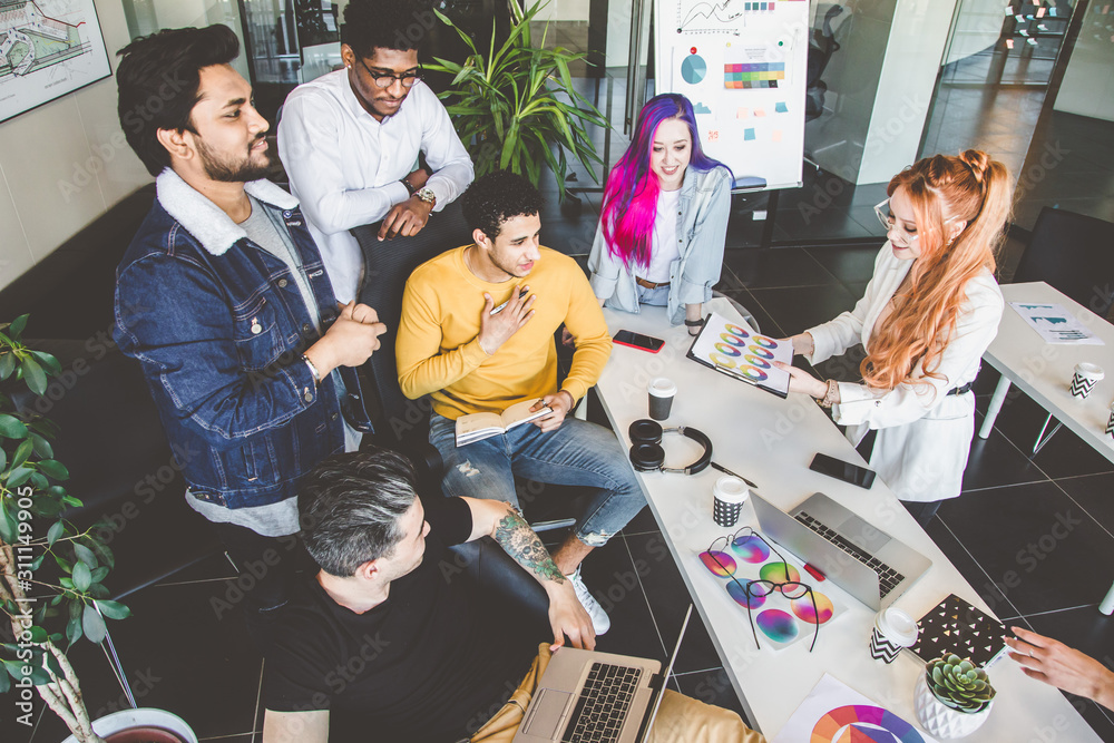 Group of multi ethnic executives discussing during a meeting. Business man and woman sitting around table at office and smiling. A team of young creative designers Group of multi ethnic executives discussing during a meeting. Business man and woman sitting around table at office and smiling. A team of young creative designers