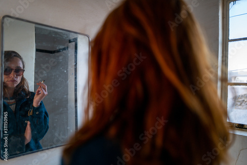 A red haired girl smokes in an abandoned motel bathroom in a desert ghost town photo