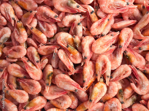 Close-up of a pile of frozen pink shrimps. Natural pink seafood background/