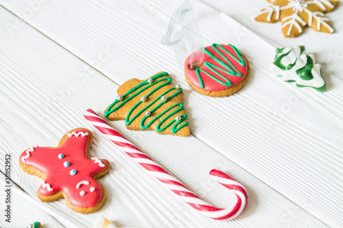 traditional Christmas sweets on white wooden background. Candy cane, round snowflake and ginger man, star lollipop. Top view. Christmas concept