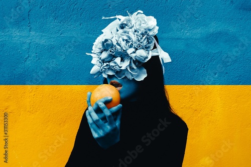 Female hand holding orange. Portrait Of Young Girl standing on color  background