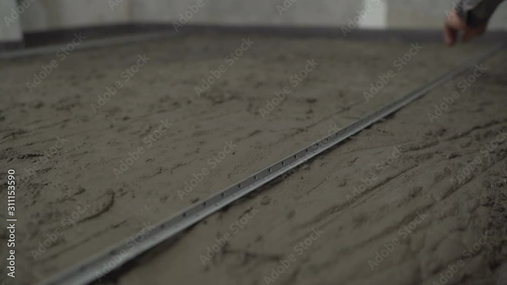 Leveling the floor with mortar and trowel. Laying self-leveling floor screed and uniformly spreading with a tool. Leveling the uneven floor. Leveling the floor with mortar and trowel. Laying self-leveling floor screed and uniformly spreading with a tool. Leveling the uneven floor.