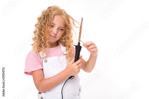 blond caucasian girl twists her hair with a hair curler on a white background