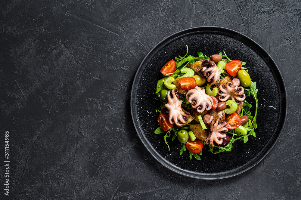 Salad with grilled octopus, potatoes, arugula, tomatoes and olives. Black background. Top view. Space for text